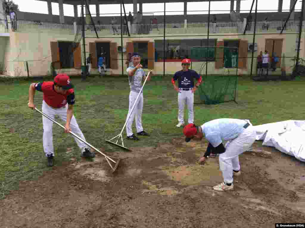 Japanese expatriates help prepare the ballfield before the start of a game.