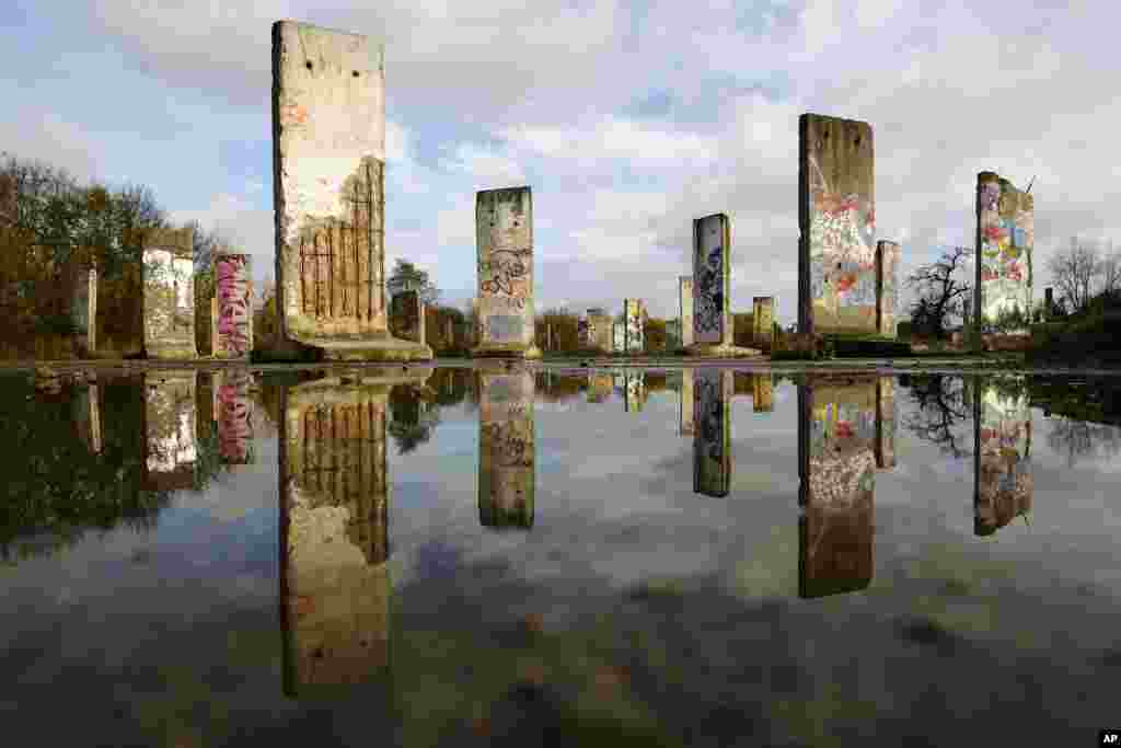 On the eve of the 24th anniversary of the fall of the Berlin Wall, original pieces of the Berlin Wall are mirrored in a pond as they are displayed for sale at the city of Teltow near Berlin, Germany. 