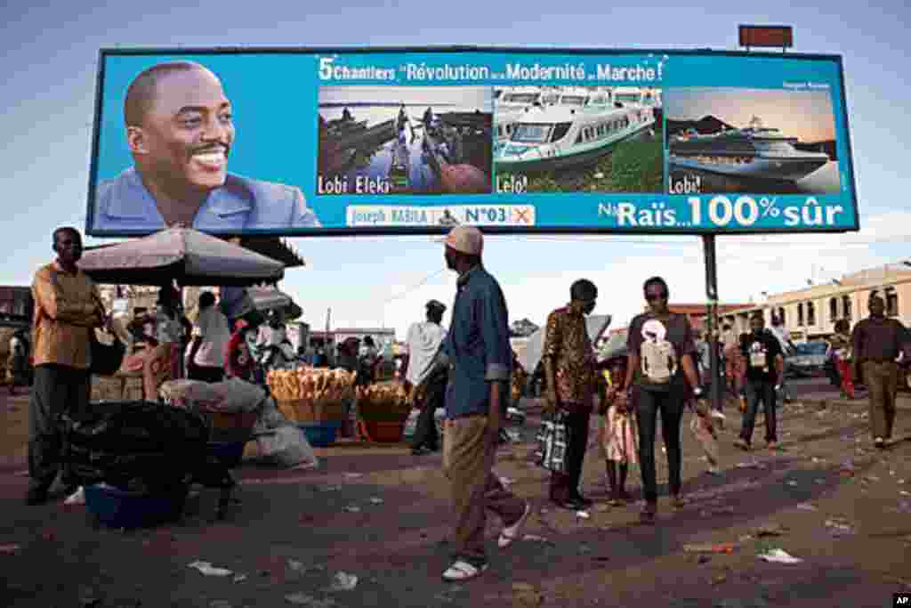 People walk under a giant poster showing Democratic Republic of the Congo 's President and candidate for a second term Joseph Kabila, in Kinshasa, November 7, 2011.