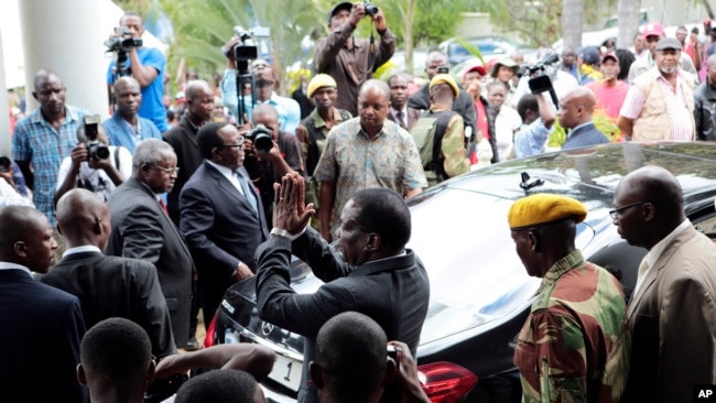 FILE - Zimbabwe President Emmerson Mnangagwa, center, leaves after paying his respects to the family of Morgan Tsvangirai, in Harare, Feb. 18, 2018.