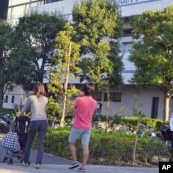 A family strolling past the Edogawa City Baseball Stadium, near where high levels of radiation has been detected this month, Japan, October 15, 2011.