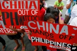 FILE - Protesters display placards during a rally at the Chinese consulate in the financial district of Makati city, east of Manila, Philippines, Nov. 12, 2015.