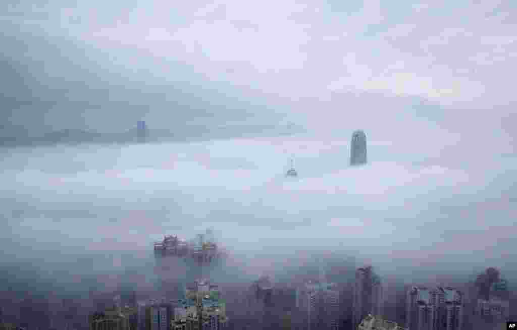 Two International Finance Centre tower, center right, and International Commerce Centre, top left, are seen over the clouds in Hong Kong.