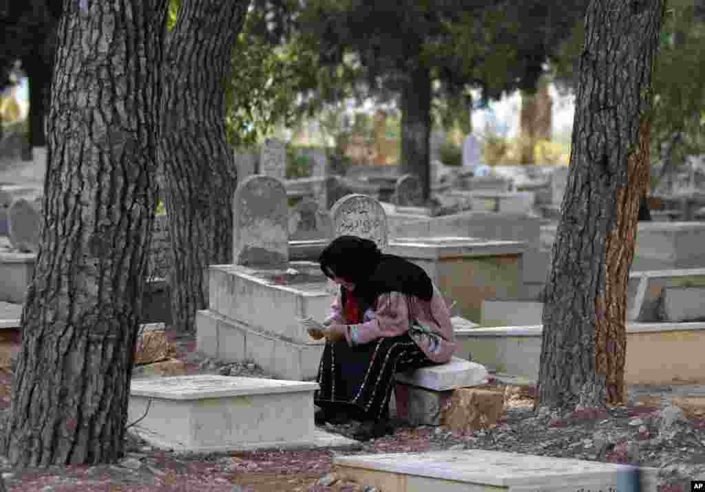 A Palestinian woman prays next to the grave of a loved one on the first day of Eid al-Adha in the West Bank city of Ramallah, October 26, 2012.