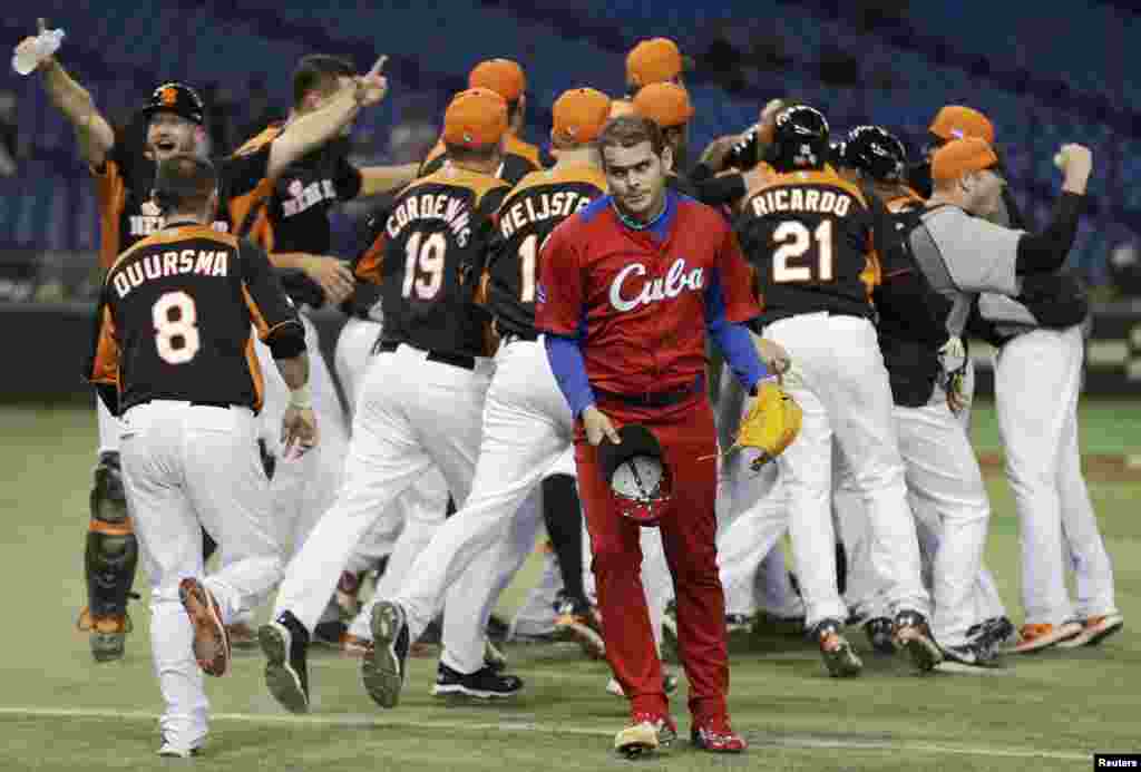 Cuba&#39;s pitcher Diosdany Castillo (C) walks off the field as Netherlands&#39; players celebrate after defeating Cuba at the World Baseball Classic (WBC) second round game in Tokyo. 