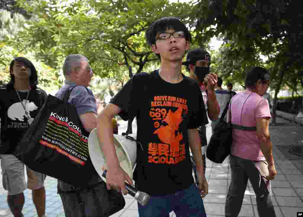 A leader of pro-democracy students Joshua Wong watches as police officers remove the barricades, Hong Kong, Oct. 14, 2014. 