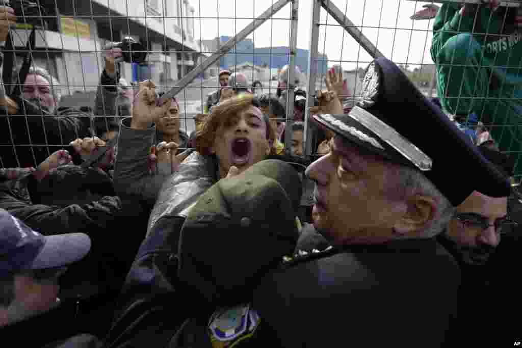 Police scuffle with Afghan migrants as they block the entrance of the Hellenikon migrant camp in southern Athens, Greece, during a visit by Migration Minister Yannis Mouzalas.