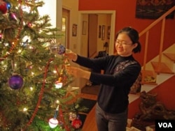 Chun Guo hangs an ornament on the Christmas tree