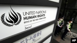 FILE - South Korean police officers stand guard by a signboard of the newly opened office of the United Nations High Commissioner for Human Rights in Seoul, South Korea.