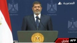 An image taken from Egyptian state TV shows Egyptian President Mohamed Morsi standing on the podium ahead of his televised address to the nation on his first year in power, in Cairo, June 26, 2013. 