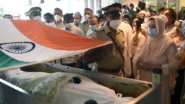 A police officer places an Indian national flag over the coffin of Bollywood icon Dilip Kumar during his funeral in Mumbai, India, Wednesday, July 7, 2021. (Kunal Patil/Pool photo via AP)