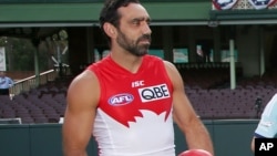 FILE - In this March 19, 2014 photo, Sydney Swans player Adam Goodes holds an Australian Rules Football at the Sydney Cricket Ground. Australians tend to laud their champions, so the fact that crowds continue to loudly boo him when he plays for the Sydney Swans in the nation-wide Australian Football League has both concerned and confounded Goodes to the point where he's considering retirement.
