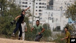 Israeli settler boys throw stones during clashes with Palestinians after a stabbing attack outside the Jewish settlement of Kiryat Arba in the West Bank, Friday, Oct. 9, 2015. 