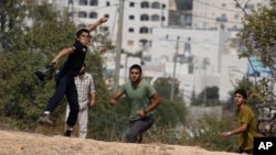 Israeli settler boys throw stones during clashes with Palestinians after a stabbing attack outside the Jewish settlement of Kiryat Arba in the West Bank, Friday, Oct. 9, 2015.