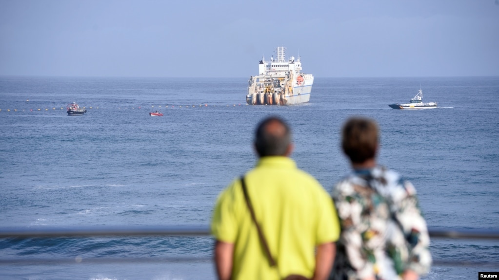 2017年6月13日，西班牙北部毕尔巴鄂附近的阿里塔拉（Arrietara）海滩，一对夫妇在观望海上的电缆铺设船。(photo:VOA)
