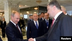 Presiden Rusia Vladimir Putin (kiri) berjabat tangan dengan Presiden Ukraina Petro Poroshenko di Minsk, Belarusia (26/8). 