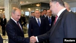 Russian President Vladimir Putin, left, shakes hands with his Ukrainian counterpart Petro Poroshenko, as Kazakh President Nursultan Nazarbayev watches, in Minsk, Aug. 26, 2014.