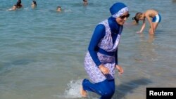 A woman wearing a burkini walks in the water August 27, 2016 on a beach in Marseille, France, the day after the country's highest administrative court suspended a ban on full-body burkini swimsuits that has outraged Muslims and opened divisions within the