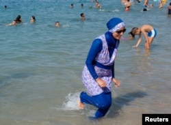 A woman wearing a burkini walks in the water August 27, 2016 on a beach in Marseille, France, the day after the country's highest administrative court suspended a ban on full-body burkini swimsuits that has outraged Muslims and opened divisions within the