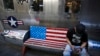 FILE - A man browses his smartphone on a bench decorated with a U.S. flag, outside a fashion boutique selling U.S. brand clothing at a shopping mall in Beijing, China, May 13, 2019.