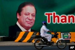 A motorcyclist drives past a billboard showing the portrait of Pakistani Prime Minister Nawaz Sharif at a main highway in Islamabad, Pakistan, July 10, 2017.