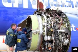 National Transportation Safety Board investigators examine damage to the engine of the Southwest Airlines plane that made an emergency landing at Philadelphia International Airport in Philadelphia, April 17, 2018.