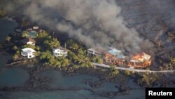 FILE - Lava destroys homes in the Kapoho area, east of Pahoa, during ongoing eruptions of the Kilauea Volcano in Hawaii, June 5, 2018.