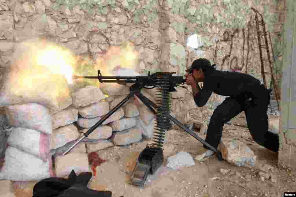 A Free Syrian Army fighter shoots his weapon near Kindi hospital, which is under the control of forces loyal to President Bashar Al-Assad, as both sides fight to take control of the hospital in Aleppo. 