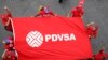 ARCHIVO - Empleados de la estatal petrolera PDVSA enarbolan una bandera con el logotipo de la compañía, en marzo de 2015, en Caracas.