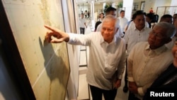 FILE - Philippines' Foreign Secretary Albert Del Rosario, points to a ancient map on display while Defense Secretary Voltaire Gazmin (R) looks on during the opening, at a Catholic university in Manila, Sept. 11, 2014. 