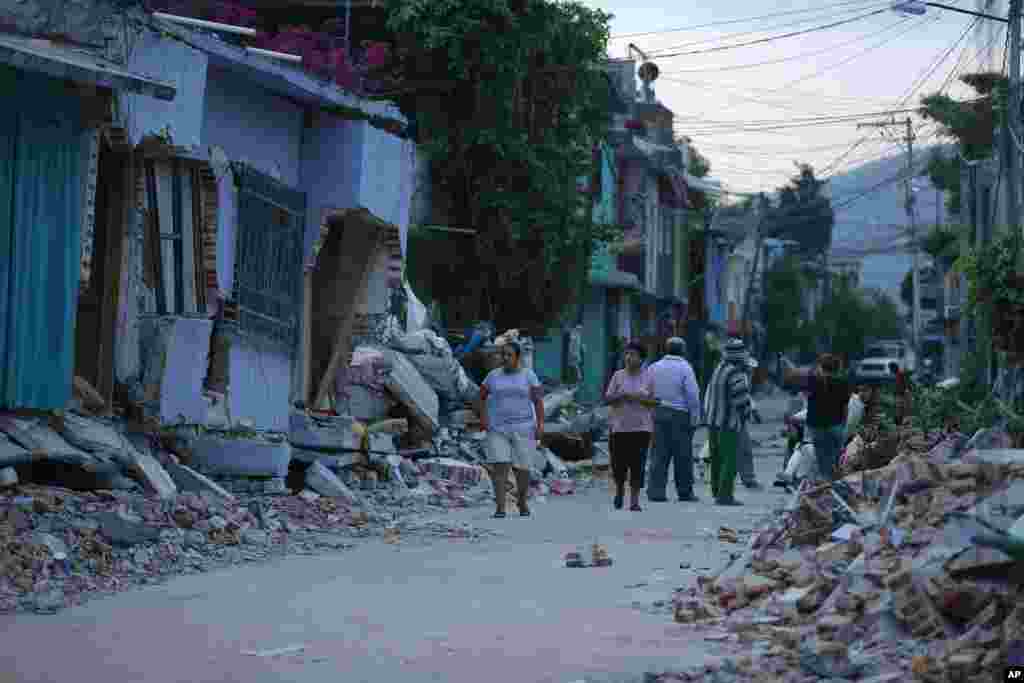 Residents stand next to buildings damaged by a strong earthquake, in Jojutla, Morelos state, Mexico, Sept. 20, 2017.