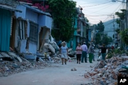 Residents stand next to buildings damaged by a 7.1 earthquake, in Jojutla, Morelos state, Mexico, Sept. 20, 2017.