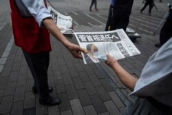 Seorang staf surat kabar Jepang membagikan salinan edisi tambahan yang berisi pengumuman PM Jepang Yoshihide Suga tidak mencalonkan diri sebagai pemimpin partai yang memerintah akhir bulan ini, di dekat stasiun kereta api di Tokyo, Jumat, 3 September 2021.