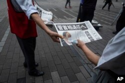 Seorang staf surat kabar Jepang membagikan salinan edisi tambahan yang berisi pengumuman PM Jepang Yoshihide Suga tidak mencalonkan diri sebagai pemimpin partai yang memerintah akhir bulan ini, di dekat stasiun kereta api di Tokyo, Jumat, 3 September 2021.