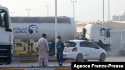 Men stand outside a storage facility of oil giant ADNOC in the capital of the United Arab Emirates, Abu Dhabi, on January 17, 2022.