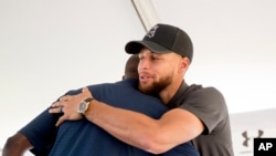 Golden State Warriors guard Stephen Curry, right, hugs Howard University President Wayne Frederick, left, during a news conference at Langston Golf Course in Washington, Monday, Aug. 19, 2019, where Curry announced that he would be sponsoring the creation