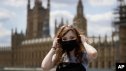 Pictured here, Estelle Fitz poses for a photo as she stands on Westminster Bridge in London, July 22, 2020. But will two masks give us more protection from the virus? (AP Photo/Kirsty Wigglesworth)