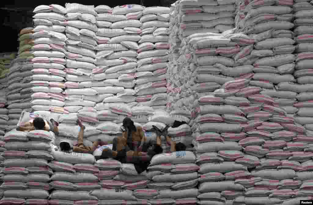 Workers take a break atop sacks of rice piled inside a warehouse of National Food Authority (NFA) in Taguig city, south of Manila, the Philippines.