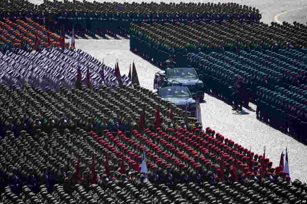 Russian Defense Minister Sergei Shoigu, center, and Commander-in-Chief of the Graund Forces and Victory Parade Commander Colonel-General Oleg Salyukov, center right, salute to soldiers as they are driven along Red Square during a rehearsal for the Victory Day military parade in Moscow.