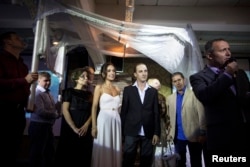 Bride Veronica (4th L) and her groom Michael (4th R), stand underneath a traditional Jewish wedding canopy during their secular wedding ceremony in Tel Aviv, Nov. 14, 2013