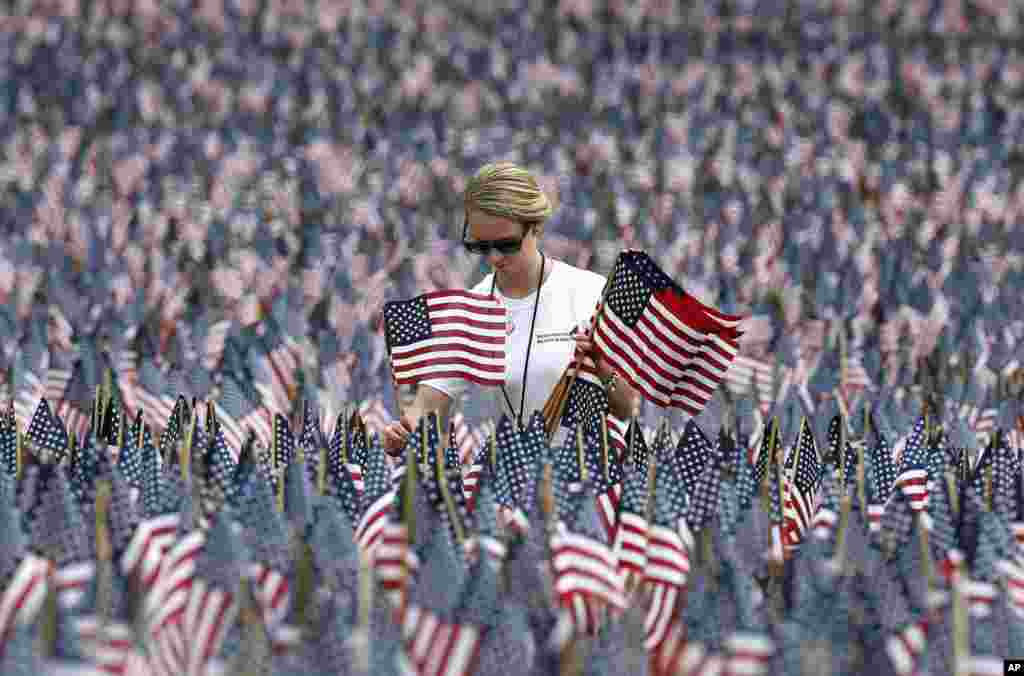 Shannon Day of Boston, a volunteer with Massachusetts Military Heroes Fund, replaces flags in the fund&#39;s flag garden on Boston Common in Boston, ahead of Memorial Day. Each of the approximately 37,000 flags represents a Massachusetts military member who died in service from the Revolutionary War to the present.