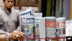 A man takes a copy of newspaper at a grocery shop in Shah Alam, Malaysia, Monday, March 26, 2018. Malaysia's government on Monday proposed new legislation to outlaw fake news with a 10-year jail term for offenders, in a move slammed by critics as a draconian bid to crack down on dissent ahead of a general election.