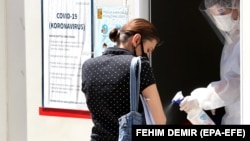 BOSNIA AND HERZEGOVINA -- A medical staff attends to a woman as she arrives to test for coronavirus, at a hospital in Sarajevo, Bosnia and Herzegovina, 08 July 2020. 