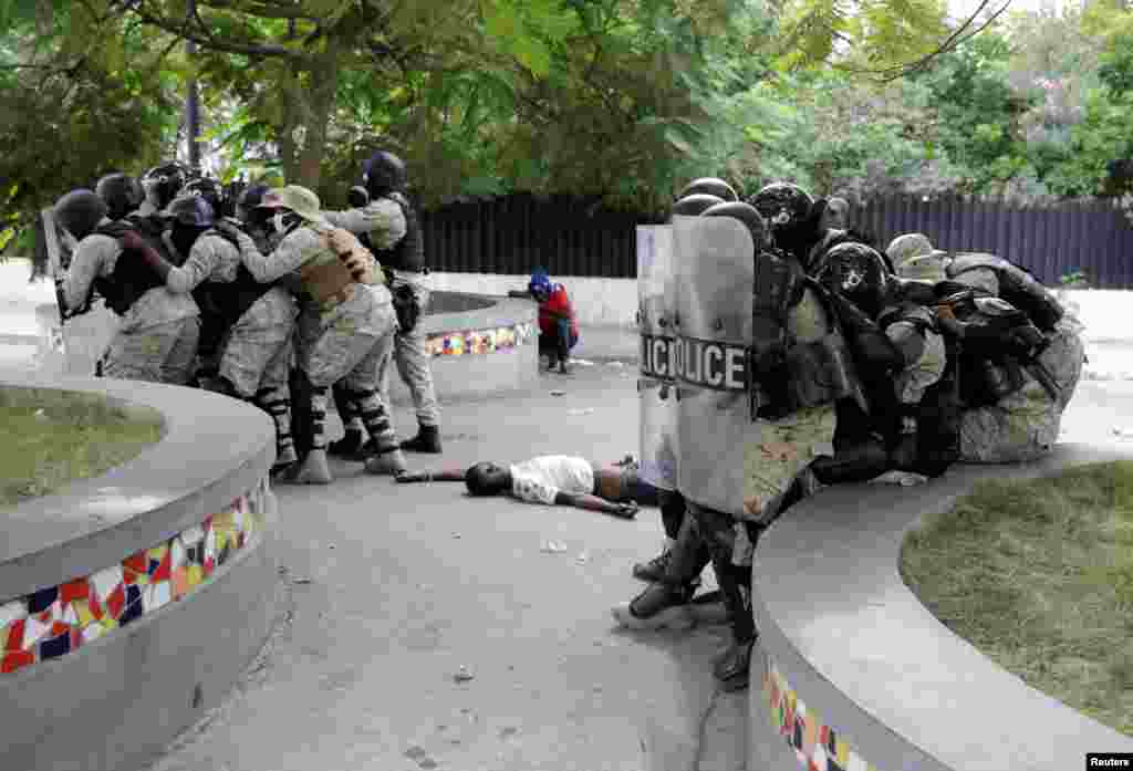 Haitian National Police (PNH) officers take position next to a dead body during clashes with protesters during a demonstration demanding the resignation of President Jovenel Moise in Port-au-Prince, Nov. 18, 2020.