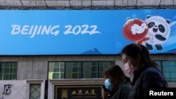 Orang-orang berjalan melewati spanduk Olimpiade Musim Dingin Beijing 2022 di Beijing, 27 Oktober 2021. (Foto: Reuters)