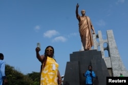 A member of a heritage tour group, traveling to Ghana to explore their ancestral roots, takes a selfie under the statue of Ghana's first president Kwame Nkrumah in Accra, August 7, 2019. Picture taken August 7, 2019. REUTERS/Francis Kokoroko