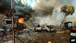 FILE - In this photo provided by the Karenni Nationalities Defense Force (KNDF), smokes and flames billow from vehicles in Hpruso township, Kayah state, Myanmar, Dec. 24, 2021.