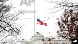 A flock of geese flies past an American flag at half-staff over the White House, Saturday, Dec. 1, 2018, in Washington. (AP Photo/Jacquelyn Martin)