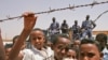 Des enfants réfugiés érythréens observent la patrouille de l'armée en arrière-plan dans le camp de réfugiés de Wad Sherrife, près de Kassala, au Soudan. 