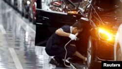 FILE - An employee works on an assembly line producing Mercedes-Benz cars at a factory of Beijing Benz Automotive Co. (BBAC) in Beijing. 